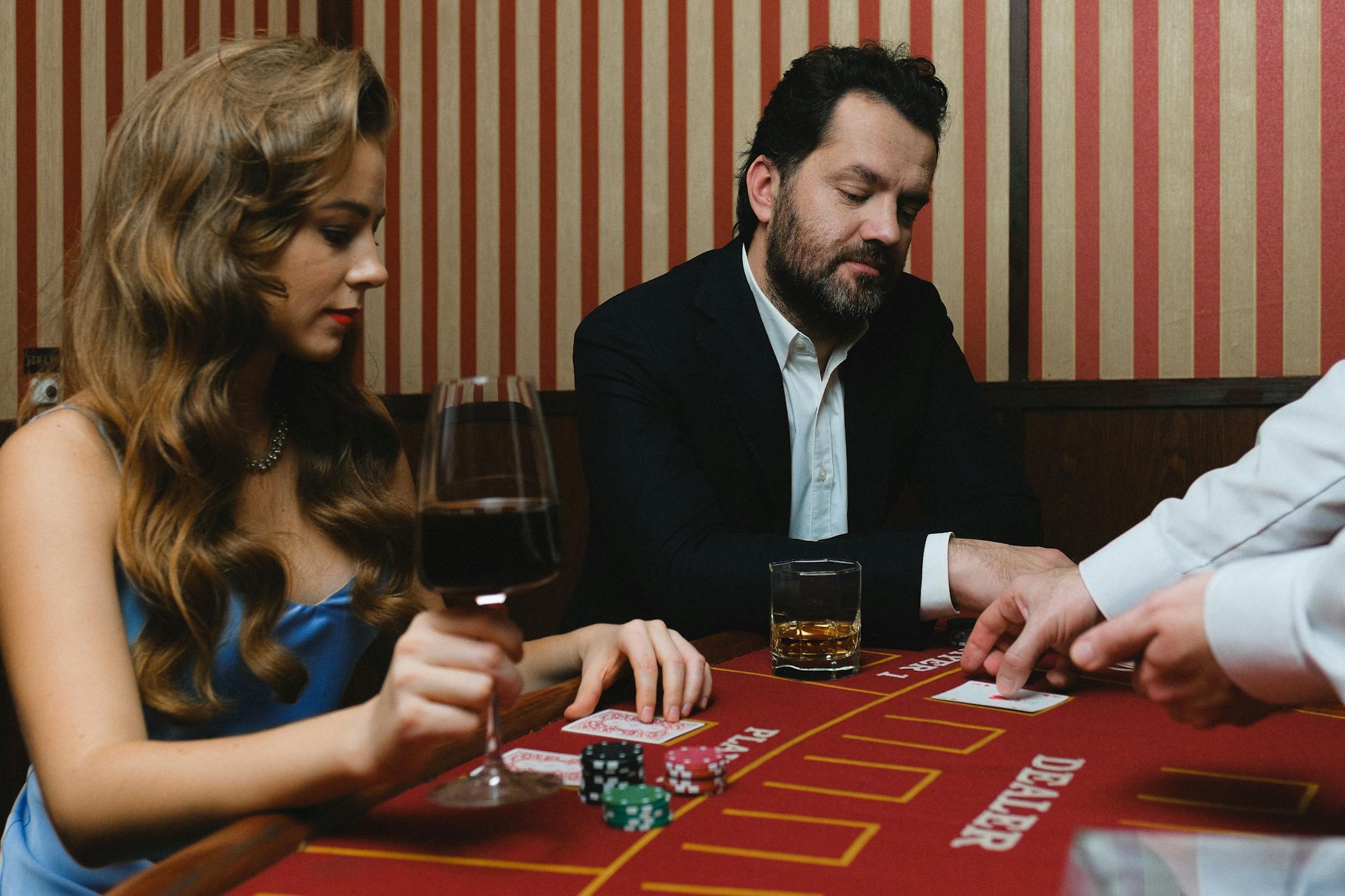 Two people play cards at a casino table with drinks, capturing the essence of elegance and risk.
